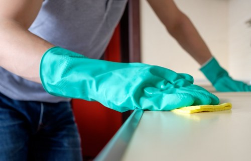 Professional cleaner sanitising office surfaces and desks